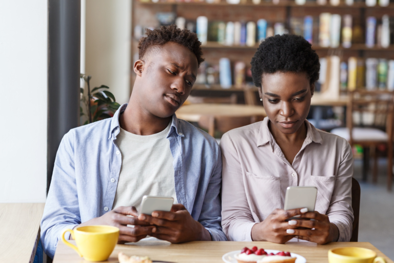 Phubbing problem. Black couple stuck in their smartphones on boring date at cafe