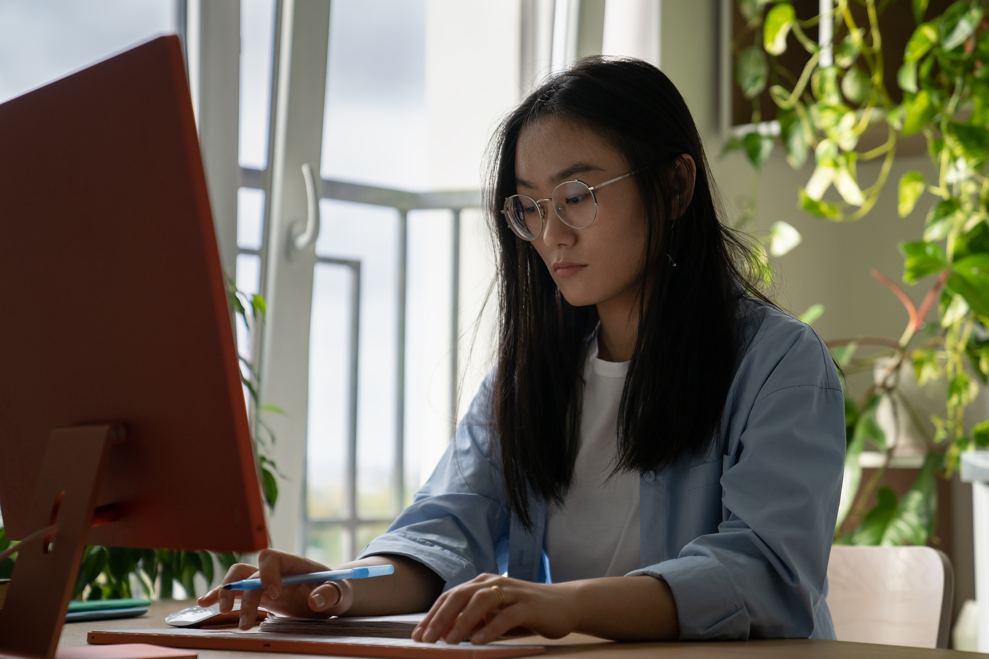 Young Asian woman freelance journalist using computer, writing for magazines and newspapers